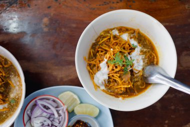 Bir kase tavuk ya da Khao Soi bifteği, turşulu sebzelerle servis edilir. Kuzey Tayland tarifi