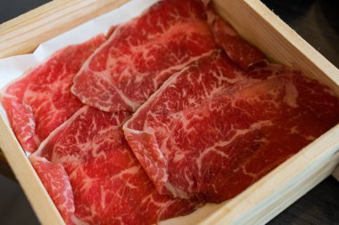 Close up shot of rare sliced beef with marbled texture served on wood box