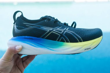 Bangkok, Tayland - 7 Ocak 2024: 25 WIDE ASICS Run Shoes Jel Nimbus ayakkabısı tutan adam. Koşu için ayakkabı spor ayakkabısı.