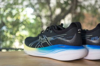 Bangkok, Tayland - 7 Ocak 2024: Ahşap masadaki Asics markasının koşu ayakkabıları. ASICS Koşu Ayakkabıları 25 genişliğinde Jel Nimbus