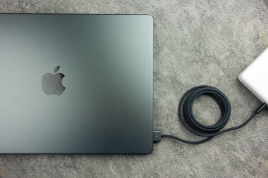 Bangkok, Tayland - 7 Ocak 2024: Siyah örgülü USB-C kablo TV 'yi kapatın ve M3 Max ile Apple Macbook Pro' ya bağlanın