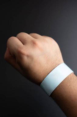 Blue paper wristband mockup on persons arm. Empty adhesive bangle wristlet sticker on male hand, blue paper bracelet, check tape, event ticket concept