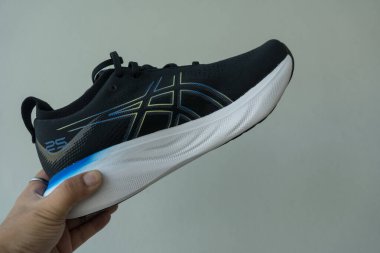 Bangkok, Tayland - 7 Ocak 2024: 25 WIDE ASICS Run Shoes Jel Nimbus ayakkabısı tutan adam. Koşu için ayakkabı spor ayakkabısı.