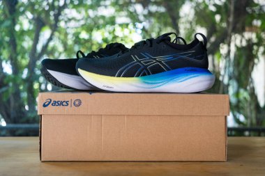 Bangkok, Tayland - 9 Ocak 2024: Yeni asik spor ayakkabıları, ASICS Koşu Ayakkabıları Jel Nimbus 25 WIDE Ahşap masadaki karton bir kutuya yerleştirildi