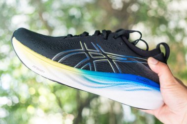 Bangkok, Tayland - 15 Ocak 2024: 25 WIDE ASICS Run Shoes Jel Nimbus ayakkabısı tutan adam. Koşu için ayakkabı spor ayakkabısı.