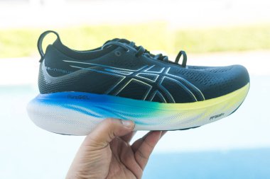 Bangkok, Tayland - 7 Ocak 2024: 25 WIDE ASICS Run Shoes Jel Nimbus ayakkabısı tutan adam. Koşu için ayakkabı spor ayakkabısı.