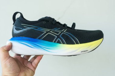 Bangkok, Tayland - 7 Ocak 2024: 25 WIDE ASICS Run Shoes Jel Nimbus ayakkabısı tutan adam. Koşu için ayakkabı spor ayakkabısı.