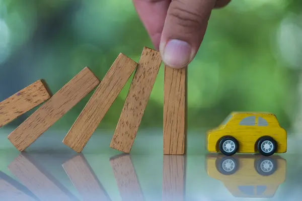 Car insurance Insurance. Hands stop the effects wooden blocks from falling to car. Business risk and strategy, Insurance concept