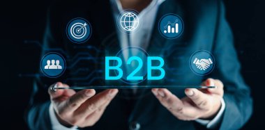 Ticaretten ticarete (B2B) pazar kavramı. B2B işlemleri, organizasyonlar arasında mal ve hizmet alışverişi. B2B yönetimi için dijital platformlar kullanarak ekranı gösteren iş adamı.