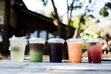 Bahçedeki ahşap masaya konmuş cam bardakta çok içecek var.