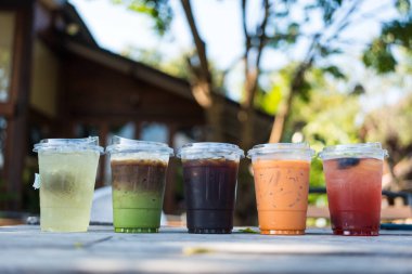 Plastik bardaklarda bir sürü soğuk içecek, doğaya aykırı bir şekilde ahşap masada. Arkadaşlık kavramı