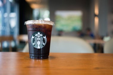 Bangkok, Tayland - 12 Nisan 2024 Starbuck Kahve buzlu americano kahvesi ahşap masa üzerinde fotokopi alanı ile