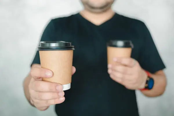 A man reaching out a brown hot coffee cup of coffee giving you.