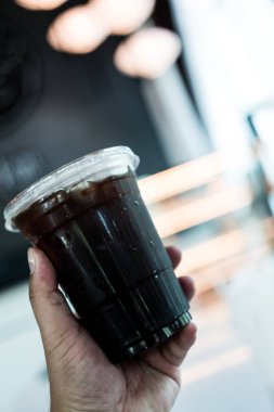 Plastik bardakta siyah kahve tutan birinin kısa bir görüntüsü var..