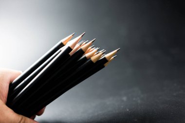 Siyah arka planda siyah bir kalemi tutan.