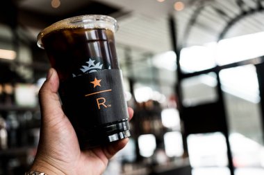 Samut Prakan, Tayland - 1 Mayıs 2024: Starbucks Reserve, Mega Bangnashop alışveriş merkezinde buzlu kahve tutan adam. Starbucks Reserve, Starbucks 'ın uluslararası kahve dükkanı zinciri.