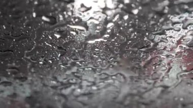 Ön camdan süzülen su dokunuşsuz bir yıkama makinesinin ön camına damlıyor.