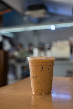 Plastik bardakta buzlu espresso kahvesi 16ons. Tahta masada.