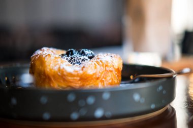 Tatlı yaban mersinli çörekleri siyah tabağa koy. Seçici odak