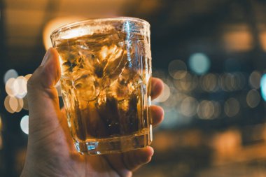 Bulanık arkaplanı olan bir bardak viski tutan adamlar.