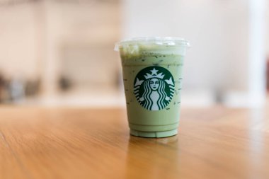 Bangkok, Tayland - 29 Mayıs 2024 Starbucks Starbucks kahvecisindeki ahşap masada buzlu kibrit yeşil çay lattesi. Seçici odak