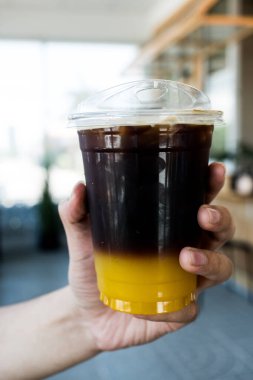 Bir bardak buzlu americano sade kahve ve portakal suyu.