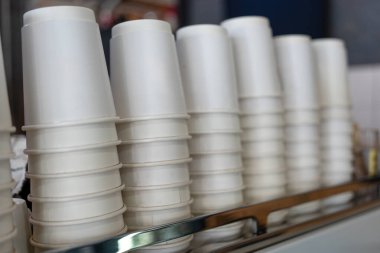 Kahve makinesinde bir sürü tek kullanımlık kağıt bardak var. Kafedeki kağıt bardak yığını.