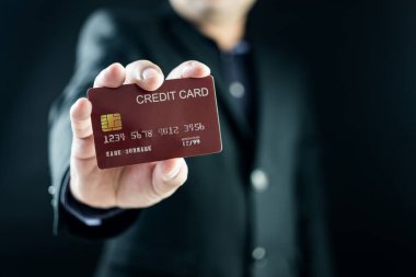 Siyah takım elbiseli yakışıklı bir işadamı kredi kartını göstererek ödeme yapıyor. İnternet kablosuz internet teknolojisi ve online alışveriş fikri