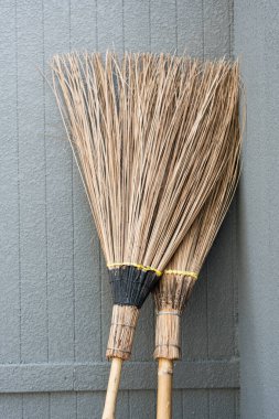 Duvara yaslanmış iki hindistan cevizi süpürgesi. Hindistan cevizi süpürgesi orijinal Tayland el yapımı, paspas temizleme ürünleri tasarımı.