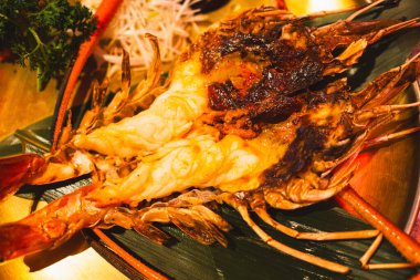 Yarısı ızgara dev nehir karidesini kesiyor, yemeye hazır. Karides kafası kremalı turuncu renkte ve son derece lezzetli olacak..
