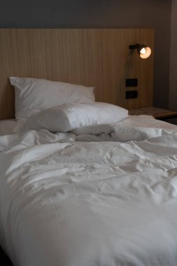Otel yatağında kırışık beyaz yastıklar, tatil konseptini rahatlatıyor.