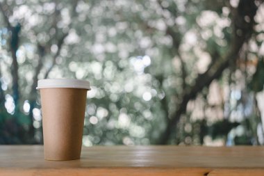 Sıcak çay için kapaklı kahverengi kağıt bardak ya da paket sıcak kahve. Kahvenin siparişi masada. Bardakta metin için boşluk var