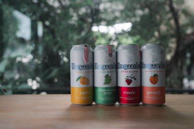Samut Prakan, Tayland - 10 Temmuz 2024: Popüler bir Hoegaarden birası Yuzu, Shine muscat üzümü, Rosee ve ahşap masaya konmuş şeftali de dahil olmak üzere dört çeşni. Tayland 'da popüler bir ithal bira.