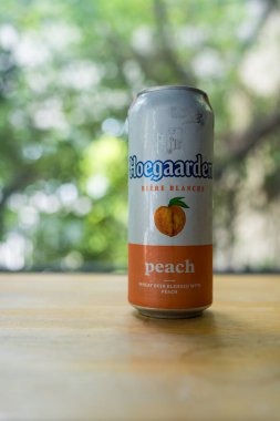 Samut Prakan, Tayland - 15 Temmuz 2024: Ahşap masada bir kutu Hoegaarden şeftalisi, şeftali ile karıştırılmış buğday birası