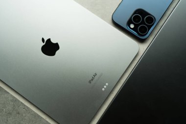 Bangkok, Tayland - 3 Ağustos 2024: iPad Air Space gray ve iPhone 15 Pro blue titanium tarafından taş masada diğer cihazlarla birlikte