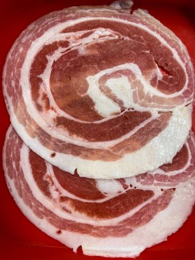 Kırmızı tepside güveç için ince domuz eti dilimleri.