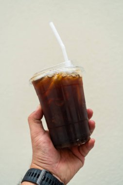 Buzlu kahve Amerikano, plastik bardakta, insan elinde.