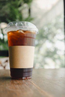 Bir bardak buzlu Amerikan kahvesi, tek kullanımlık uzun bir bardakta, kahverengi kağıt kollu bardakta.