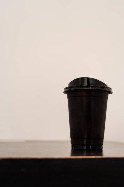 Masanın üzerinde siyah plastik buzlu kahve.