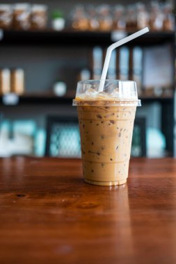 Tek kullanımlık bir bardakta, ahşap masada buzlu espresso.