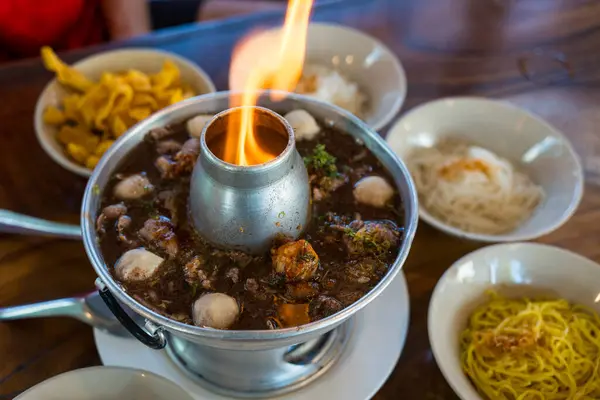 stock image Thai beef soup with braised beef, sliced beef, meatball and vegetable served in fire hot pot during fire is burning