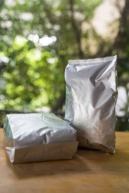 Tahta sehpanın üzerinde kahve çekirdeği için folyo poşeti.