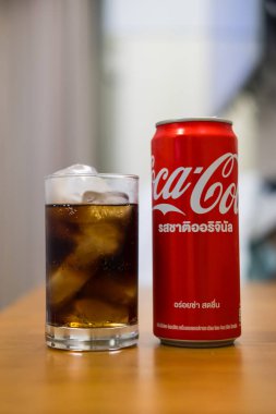 Bangkok, Tayland - 24 Ağustos 2024: konserve ve ahşap masadaki buzlu bir bardak Coca-Cola. Kokain dükkanlarda, restoranlarda satılan karbonatlı bir meşrubattır.