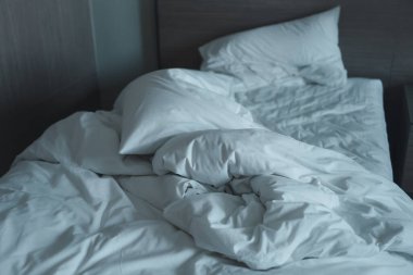 Dağınık yatak. Yatağında battaniyesi olmayan beyaz bir yastık. Sabahtan sonra rahatlama kavramı.