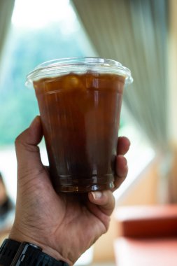 Birisi bir kafede soğuk kahve tutuyor.