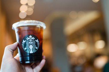 Bangkok, Tayland - 16 Eylül 2024: İçmeden önce elinde bir fincan Starbucks buzlu kahvesi tutan adam.