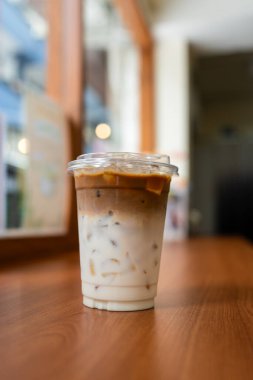 Kafedeki ahşap bir masada iki kat taze süt ve espresso ile buzlu latte kahve. Yaz içeceği konseptini tazelemek