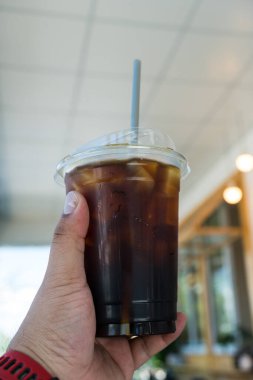 Kahve dükkanında biri elinde plastik bir bardak Americano tutuyordu.