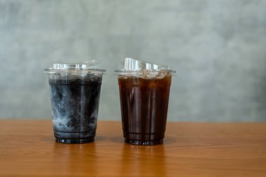 Buzlu kömür latte ve ahşap bir masada buzlu Americano..