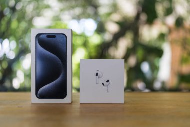 Bangkok, Tayland - 16 Ekim 2024: iPhone 15 pro ve AirPods 3 nesildir doğaya karşı ahşap masa üzerinde ambalaj